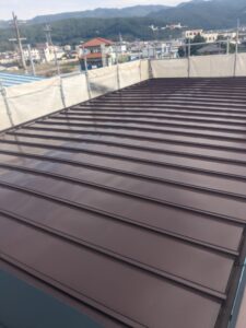 松本市A様邸 屋根 中塗り作業の様子。均一に塗り重ねてツヤを出している途中工程。