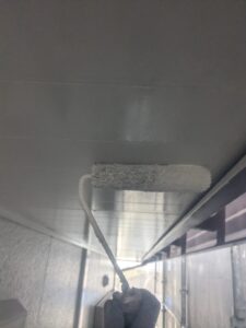 松本市A様邸 軒天の下塗り作業中。上を向きながら、湿気に強い塗膜を丁寧に塗り広げている。